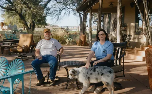 A couple and their dog sit outside