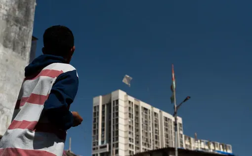 a boy looks up at a tall building