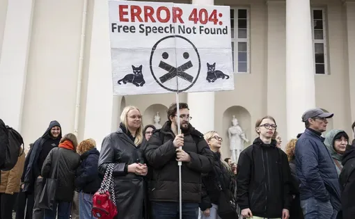 a protester holds a sign saying "Error 404: free speech not found"