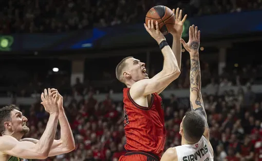 a basketball player jumps over the defense to make the shot