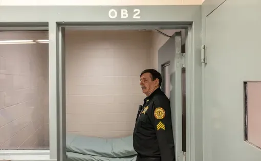 Sgt. Alan Wintle, a corrections officer at the Piscataquis County Jail in Dover-Foxcroft, stands in the doorway of an observation cell where people withdrawing off drugs and alcohol are temporarily held. Photo by Greta Rybus for The Maine Monitor.