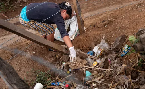 A resident of Guatemala’s Santa María Xalapán mountains gathers litter, most of it plastic, from under a fence along the road through the region during a community cleanup organized by Soila Elizabeth Cruz.