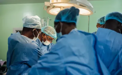Surgeons wearing blue scrubs operate.