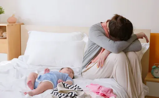 A stressed out mom and baby on a bed