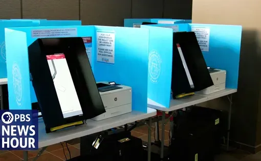voting machines on tables separated by blue trifold barriers