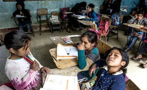 An empty desk where Baldemar Lucas García Alonzo once sat sits against the wall at the primary school in Bulej, Guatemala. Baldemar left with his father the previous week for the U.S. Image by  Simone Dalmasso / The Arizona Daily Star. Guatemala, 2019.