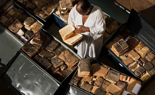 Ancient manuscripts from Mali, Niger, Ethiopia, Sudan and Nigeria line storage cases at Abdel Kader Haidara's home, the director of Bibliotheque Mama Haidara De Manuscripts, Timbuktu. These manuscripts are waiting their turn to be cataloged and added to the library collection. Inside them is a history of Africa from the 11th century onwards, with dialogue on Islam, trade, history, the law and so on. Image by Brent Stirton, National Geographic, September 2009.