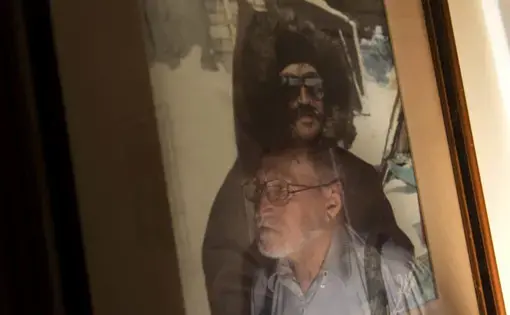 Alex Saunders, 78, is reflected in a an earlier picture of himself from the early 80’s, at his home in the military base town of Happy Valley-Goose Bay, Labrador. Saunders, of First Nations heritage, was raised learning how to survive in harsh sub-arctic environments. Image by Michael G. Seamans. Canada, 2019.