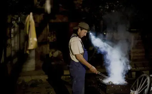 Andrei Gruber roasting meat. Image by Nadia Shira Cohen. Romania, 2011.