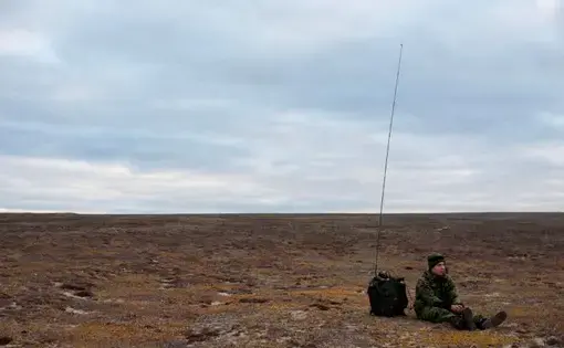 A soldier waits by his radio on the tundra near Blue Fox Harbor on Banks Island in the Canadian Arctic. The soldier was part of Operation Nanook, an annual “sovereignty operation,” in which Canadian forces patrol the nation’s northern territory. Image by Louie Palu. Canada, 2018.