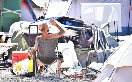 A homeless man sits by his belongings at the Lots, an outdoor encampment in Phoenix, on June 24. Summer temperatures in Phoenix consistently exceeded 110 degrees Fahrenheit, sometimes hitting 118. Image by Steve Carr/Human Services Campus. United States, 2020.