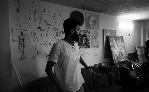 Emsallam Hdaib looks at his artwork in his Amman studio. Image by Aman Madan. Jordan, 2017.