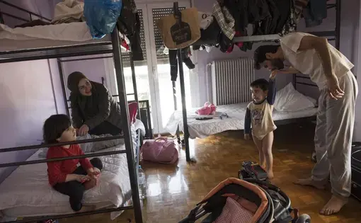 Syrian refugee, Taima, prepares to take her 6-month-old daughter, Heln, for a visit to the Acropolis, while her husband, Muhannad Abzali, 28, jokes around with their other child, Wael, 3, at the temporary apartment they are staying at in Athens. Image by Lynsey Addario. Greece, 2017.