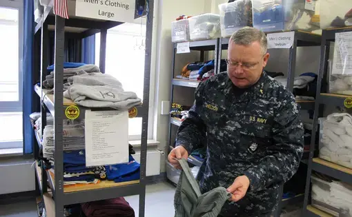 Cmdr. Joseph Sheldon, a Navy chaplain, examines a pair of pants that have been taken apart and installed with Velcro so a wounded soldier can dress themselves. Image by Meg Jones. Germany, 2011.