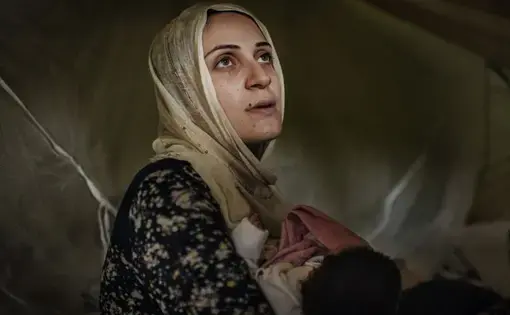 Taimaa Abazli, 24, holds her new baby Heln in their tent at the Karamalis camp in Thessaloniki. Image by Lynsey Addario for TIME. Greece, 2016.