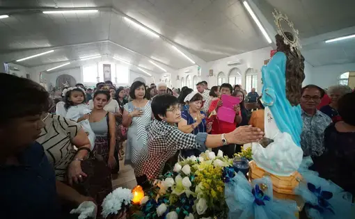 Parishioners pay their respects during a Mass held in honor of the Assumption of Our Lady in Piti, Guam. Image by Cory Lum. Guam, 2017.