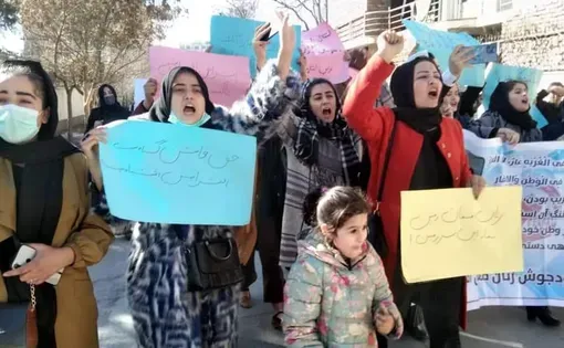 Women and a girl hold signs and protest