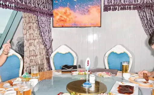 At lunchtime on a boat on the Taedong River, the state TV channel broadcasts images of artillery, missiles, and fighter jets. Image by Max Pinckers/The New Yorker. North Korea, 2017.