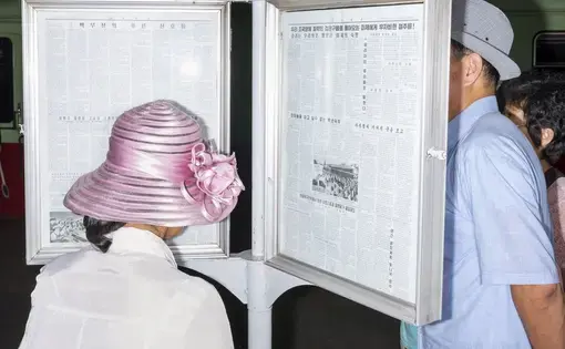 Commuters reading the official newspaper on a Pyongyang Metro platform. Image by Max Pinckers/The New Yorker. North Korea, 2017.