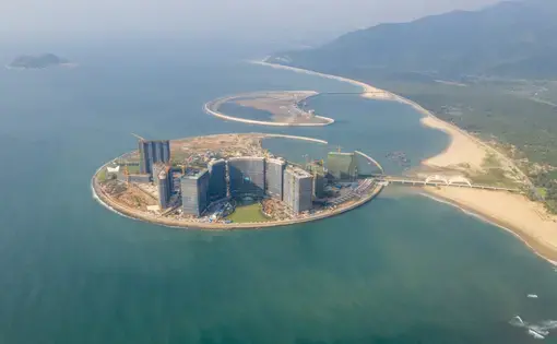 Two islands in the shape of the sun and a crescent moon have been artificially made off Hainan’s east coast, in the Sun and Moon Bay (Riyuewan), a surfing destination 25 km south of Wanning city. The two man-made islands make up about 1 square kilometre, and are planned as a tourism site with a theme park, international conference venues, shopping malls, yacht club and luxury hotels.The land reclamation on the main island—that resembles a round sun—was completed in 2014 and beach erosion was found soon after. The erosion poses a threat to a forest of Vatica Mangachapoi which grows on sandy beaches in Hainan. The endangered plant is protected in China as it has already suffered over-cutting for its valuable wood. In addition, the reclamation project will destroy 50,000 sqm coral reef. Chinese press reports say the project started without carrying out a thorough environmental impact assessment. When these photographs were made in October 2018, construction appeared to still be going on. Italy-based design and… Two islands in the shape of the sun and a crescent moon have been artificially made off Hainan’s east coast, in the Sun and Moon Bay (Riyuewan), a surfing destination 25 km south of Wanning city. The two man-made islands make up about 1 square kilometre, and are planned as a tourism site with a theme park, international conference venues, shopping malls, yacht club and luxury hotels.The land reclamation on the main island—that resembles a round sun—was completed in 2014 and beach erosion was found soon…