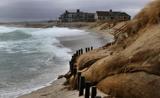 During a nor'easter, surf washed up close to the dunes where homes stand facing Town Neck Beach. Image by John Tlumacki. United States, 2019.