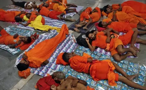 Kanwarias, worshippers of the Hindu god Shiva, sleep as they wait for their train before a ritual pilgrimage at a railway station in Allahabad, India, on July 29, 2018. Image by Rajesh Kumar Singh / AP. India, 2018.