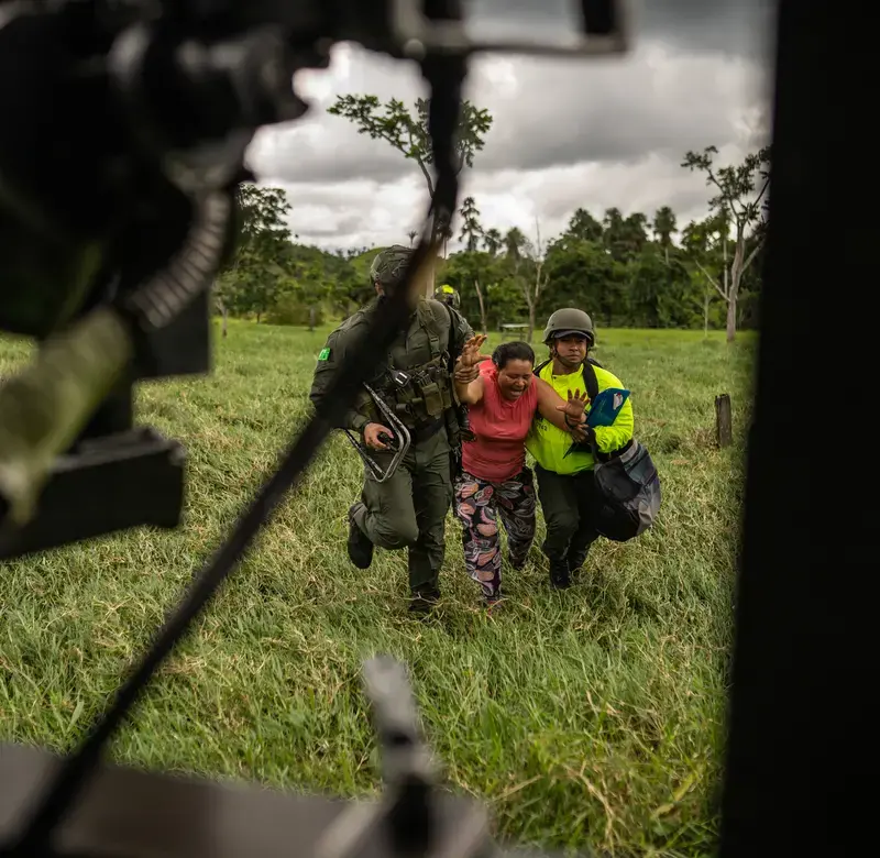 two soldiers carry a woman by the arms into a waiting helicopter