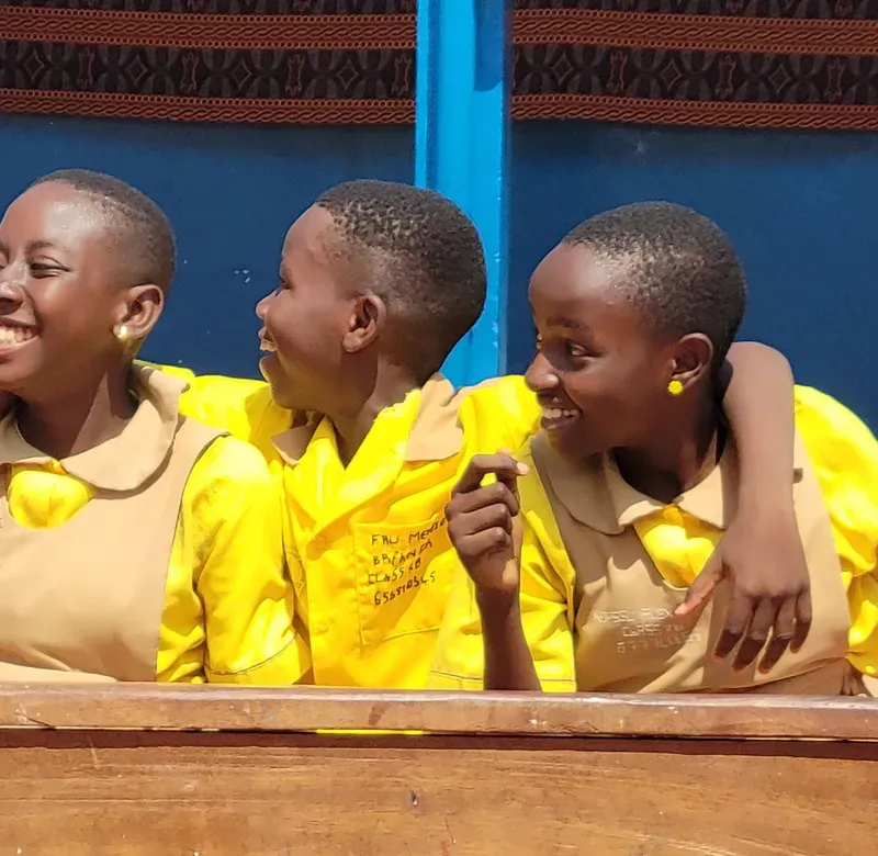 a group of young boys in yellow shirts sit together laughing