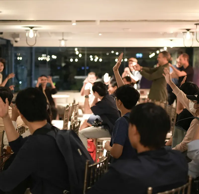 a captive audience at a show raises their hands in participation
