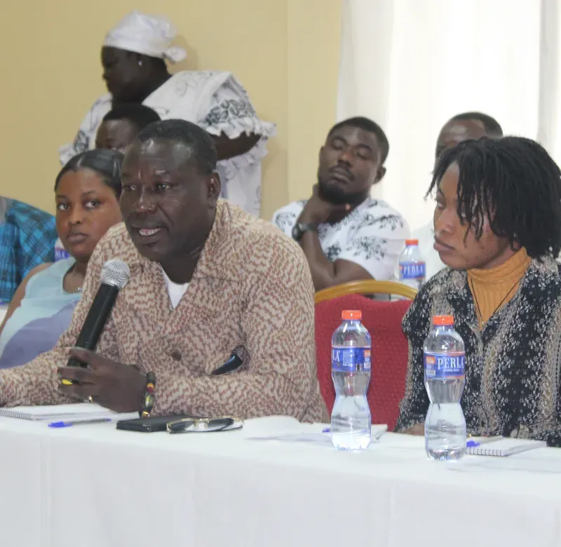 a group of conference attendees sit at a table and listen to someone speaking