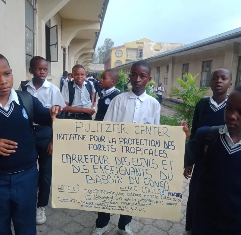 a group of schoolchildren hold a handwritten posterboard