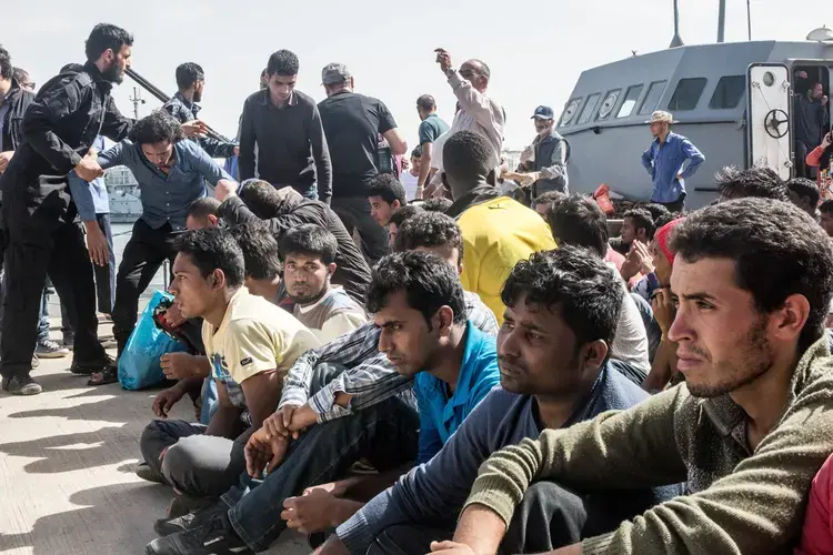 Migrants from Bangladesh and Morocco disembark a warship operated by the Libyan navy after their boat was intercepted at sea. Image by Peter Tinti. Libya, 2017.
