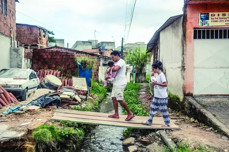 Nascimento e seu marido Luiz, atravessam um riacho aberto com sua filha, Valentina, voltando da casa dos avós de Dhulha. Fotografia por Fábio Erdos. Brazil, 2017.