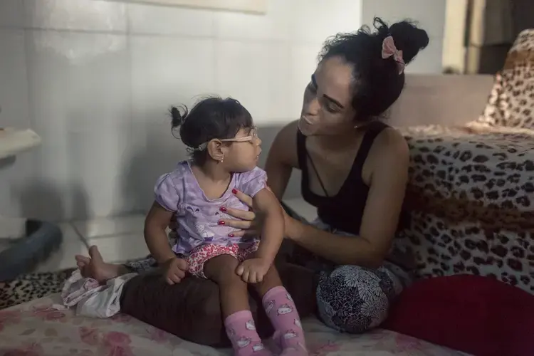 Mãe e filha: Dhulha Alen Silva do Nascimento e sua filha, Valentina compartilham um momento de silêncio em casa. Fotografia por Fábio Erdos Brazil, 2017.