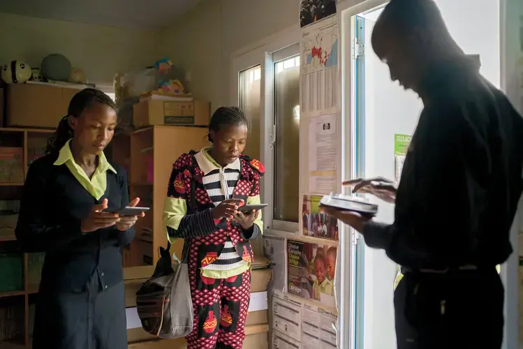 Bridge teachers at a school in Kiserian, Kenya, receiving their lesson plans via e-readers. Image by Diana Zeyneb Alhindawi for The New York Times. Kenya, 2017.<br />