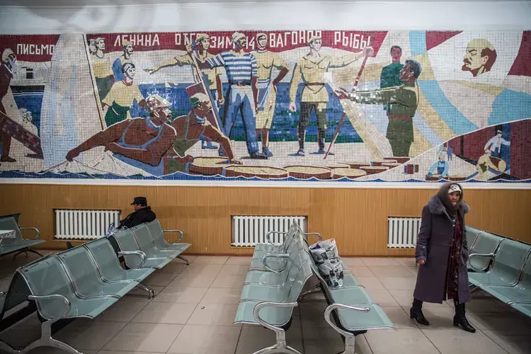 People wait for a train under a Soviet-era mural in Aralsk. Image by Taylor Weidman. Kazakhstan, 2017.