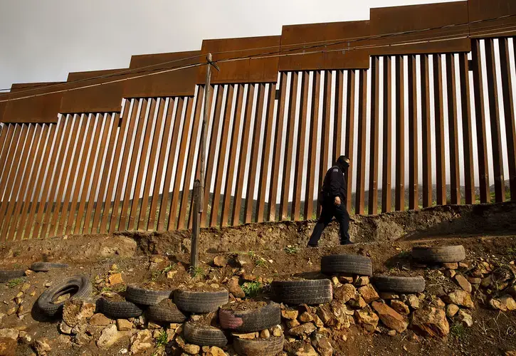 A Mexico Federal Police officer walks near the border fence in East Tijuana. Image by Erika Schultz. Mexico, 2019.