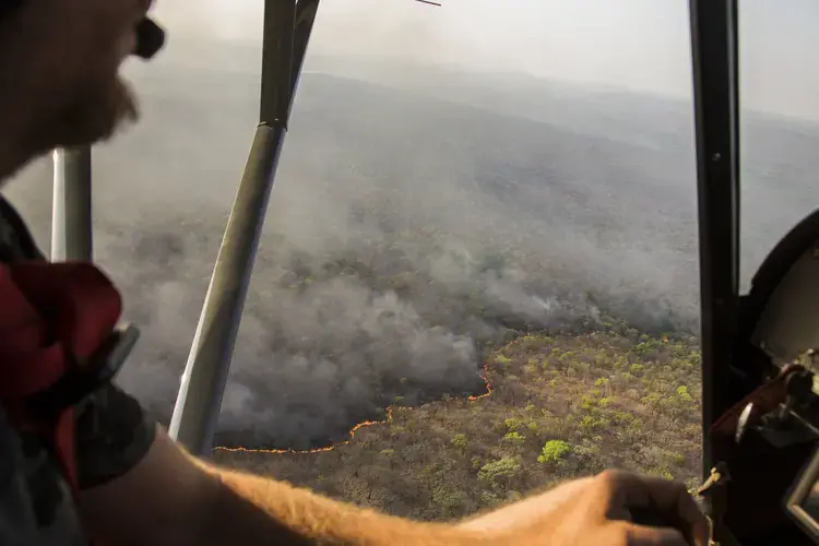 Cédric Ganière flies over a bush fire on the Chinko savannah in his tiny, two-seater plane during a mission to spot cattle herders and blazes. Image by Jack Losh. Central African Republic, 2018.