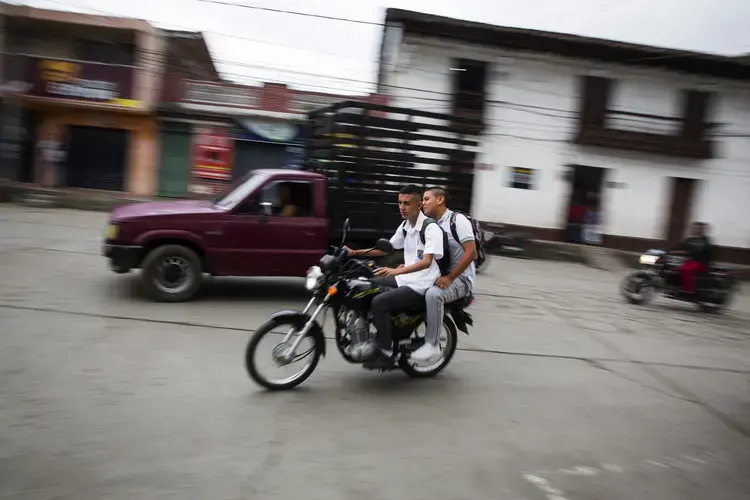 Young men on a motorcycle pass through the central town square in La Union, Colombia on Tuesday, March 6, 2018. Image by Greg Kendall-Ball. Colombia, 2018.
