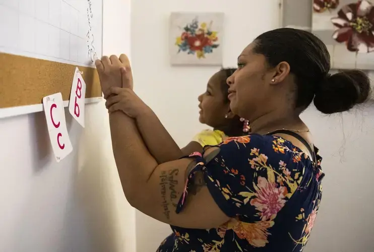 Tyra Johnson helps her daughter Madison Hundley, 4, write 'chair' on the whiteboard during a home-school lesson at her house in St. Louis. Johnson has set up a strict daily schedule for distance learning. Image by Colter Peterson / Post-Dispatch. United States, 2020.