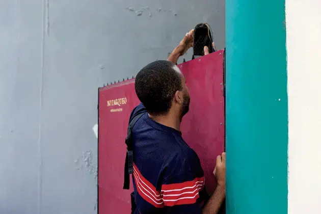 Maykel Molina Gutiérrez delivers El Paquete to a customer during his weekly round. Image by Alexa Hoyer. Cuba.