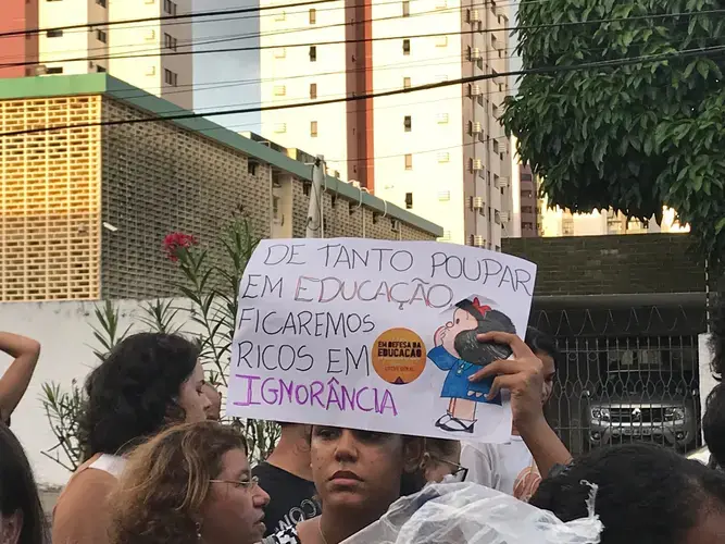 A protester's sign reads “For as long as we save spending on education, we will be rich in ignorance.” Brazil, 2019. Image by Rafael Lima.