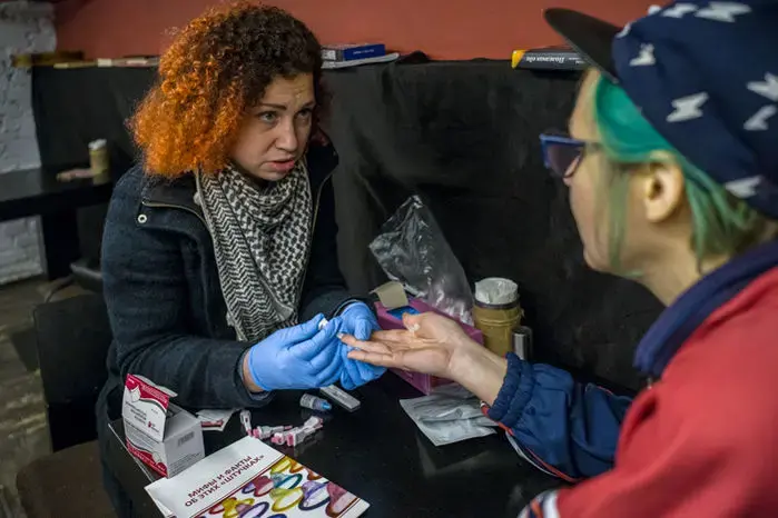 Maria Jacovleva (left), who directs the nongovernmental organization Candle, does HIV testing at a St. Petersburg vegan bar, Animal. Image by Misha Friedman. Russia, 2018.