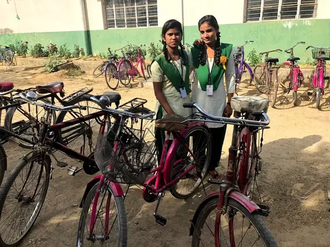 Sonam, with a friend, stands by her bicycle outside Pardada Pardadi's school. Image by Annalisa Merelli. India, 2018.