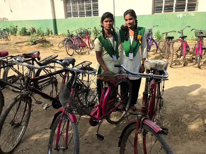 Sonam, with a friend, stands by her bicycle outside Pardada Pardadi's school. Image by Annalisa Merelli. India, 2018.