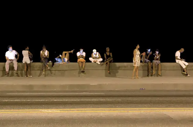 Cubans using Wi-Fi on the Malecón, in one of the fifty-three Wi-Fi zones in Havana. Image by Alexa Hoyer. Cuba.<br />
