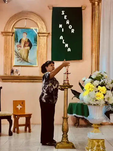 A parishioner lights a ceremonial candle before the mass. Image by Lily Moore-Eissenberg. Mexico, 2019.