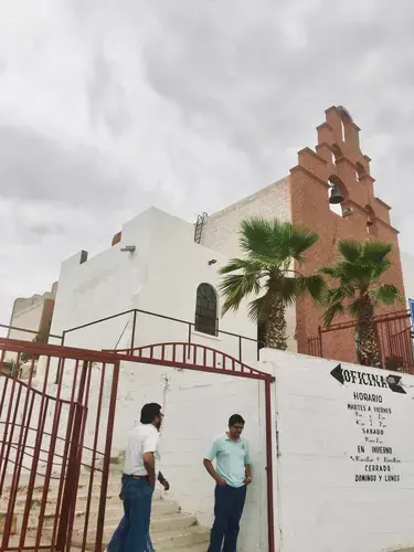 A priest talks with a friend outside his Juárez parish, which he has converted into a migrant shelter. Image by Lily Moore-Eissenberg. Mexico, 2019.