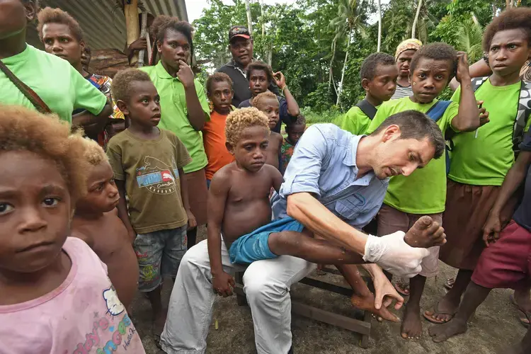 Oriol Mitjà, whose work has triggered a new yaws eradication effort, examines a young patient named Jeremiah, who has an active infection, but can be cured with a dose of azithromycin. Image by Brian Cassey. Papua New Guinea, 2018.