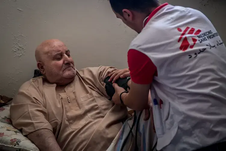 A physician checks on Ibrahim Hassan (left), who lives as a displaced person in Jordan after fleeing the regime in Syria. Image by Neil Brandvold. Jordan, 2017.